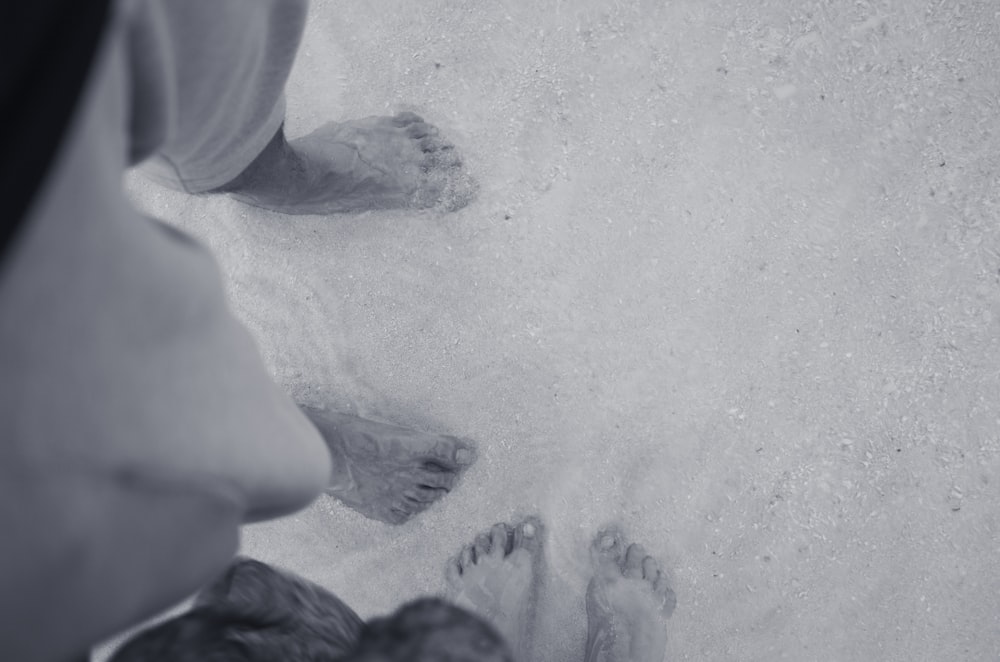 person in black pants and black shoes standing on gray sand