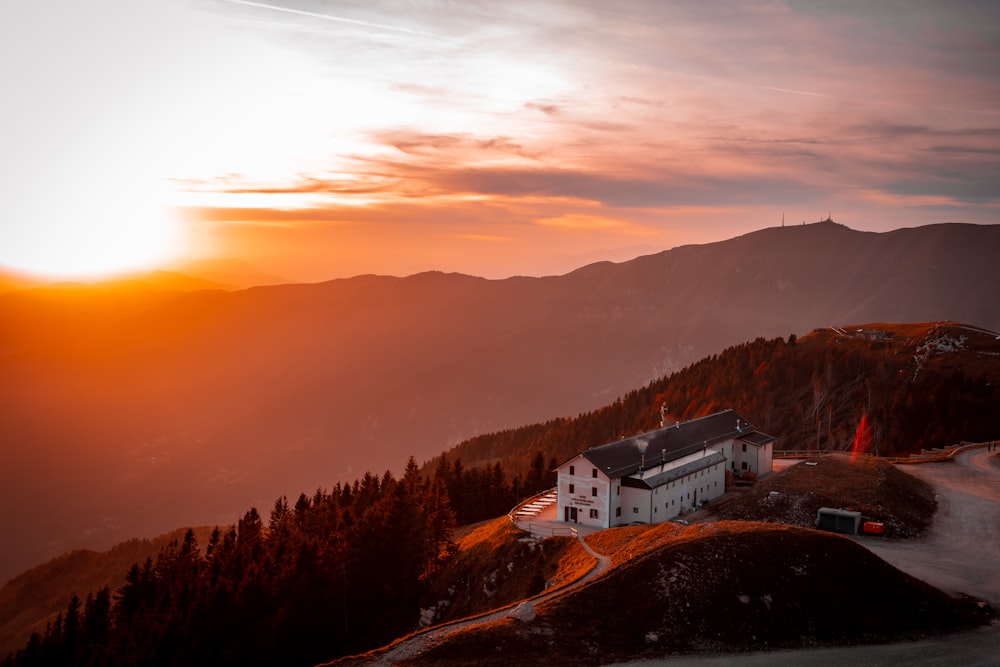 casa branca e marrom no topo da montanha durante o pôr do sol