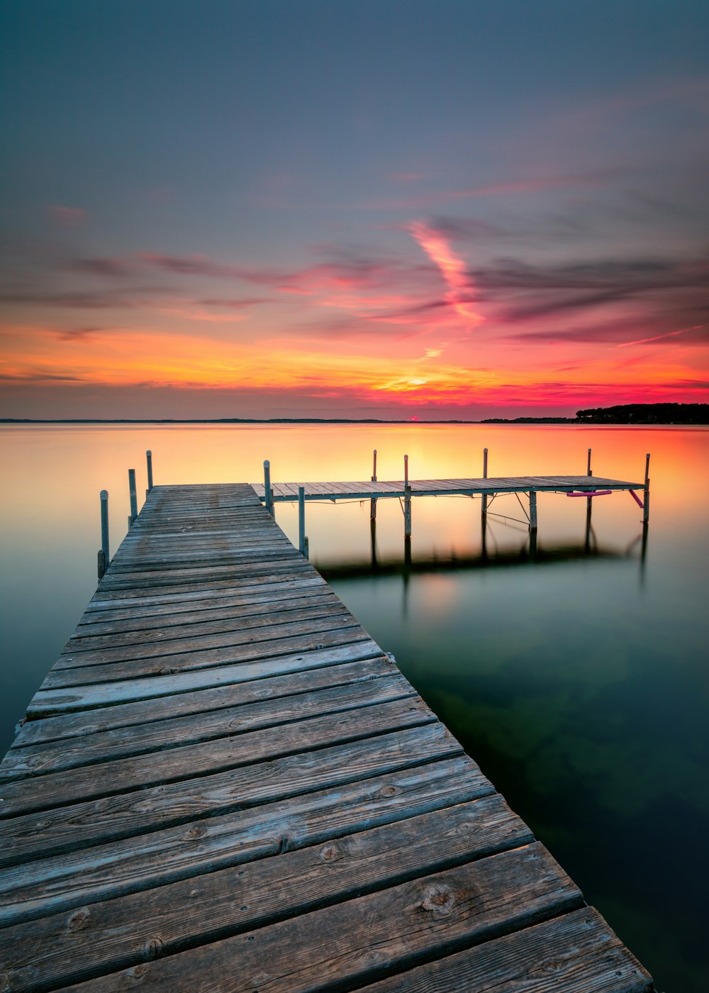 Braunes Holzdock auf ruhigem Wasser bei Sonnenuntergang