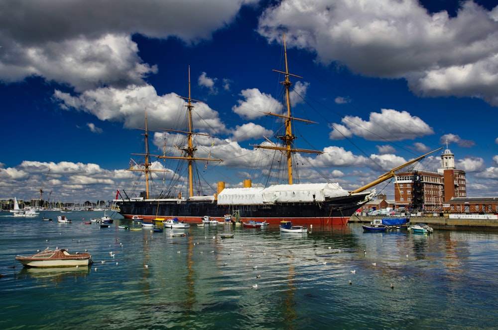 weißes und braunes Schiff auf See unter blauem Himmel und weißen Wolken tagsüber