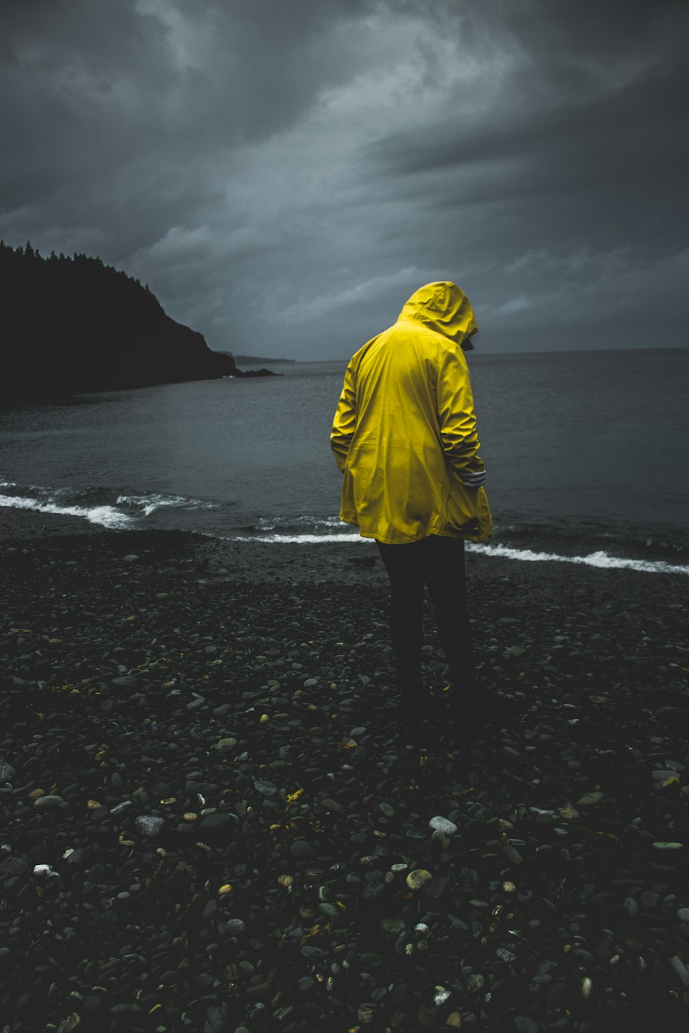 person in yellow hoodie standing on seashore during daytime