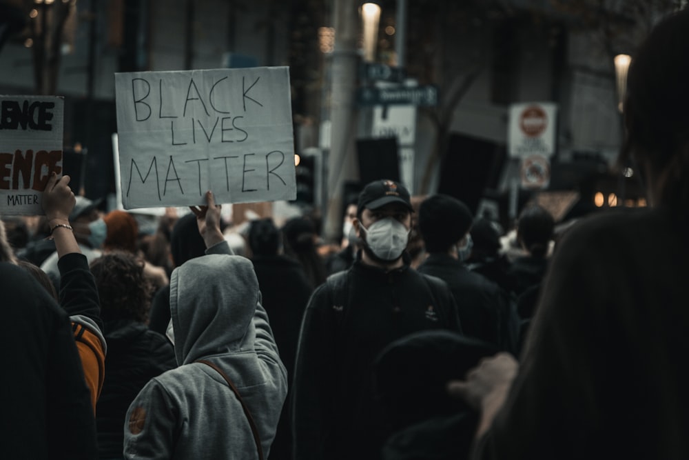 man in black hoodie standing in front of people during nighttime