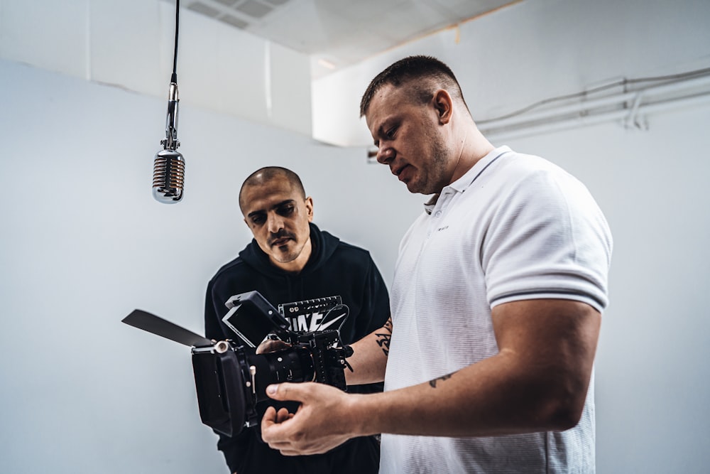 man in white crew neck t-shirt holding black camera