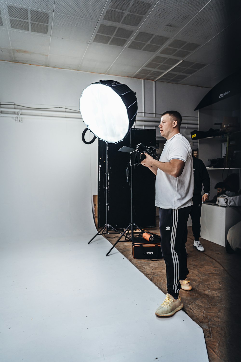 man in white t-shirt and black pants standing near white wall