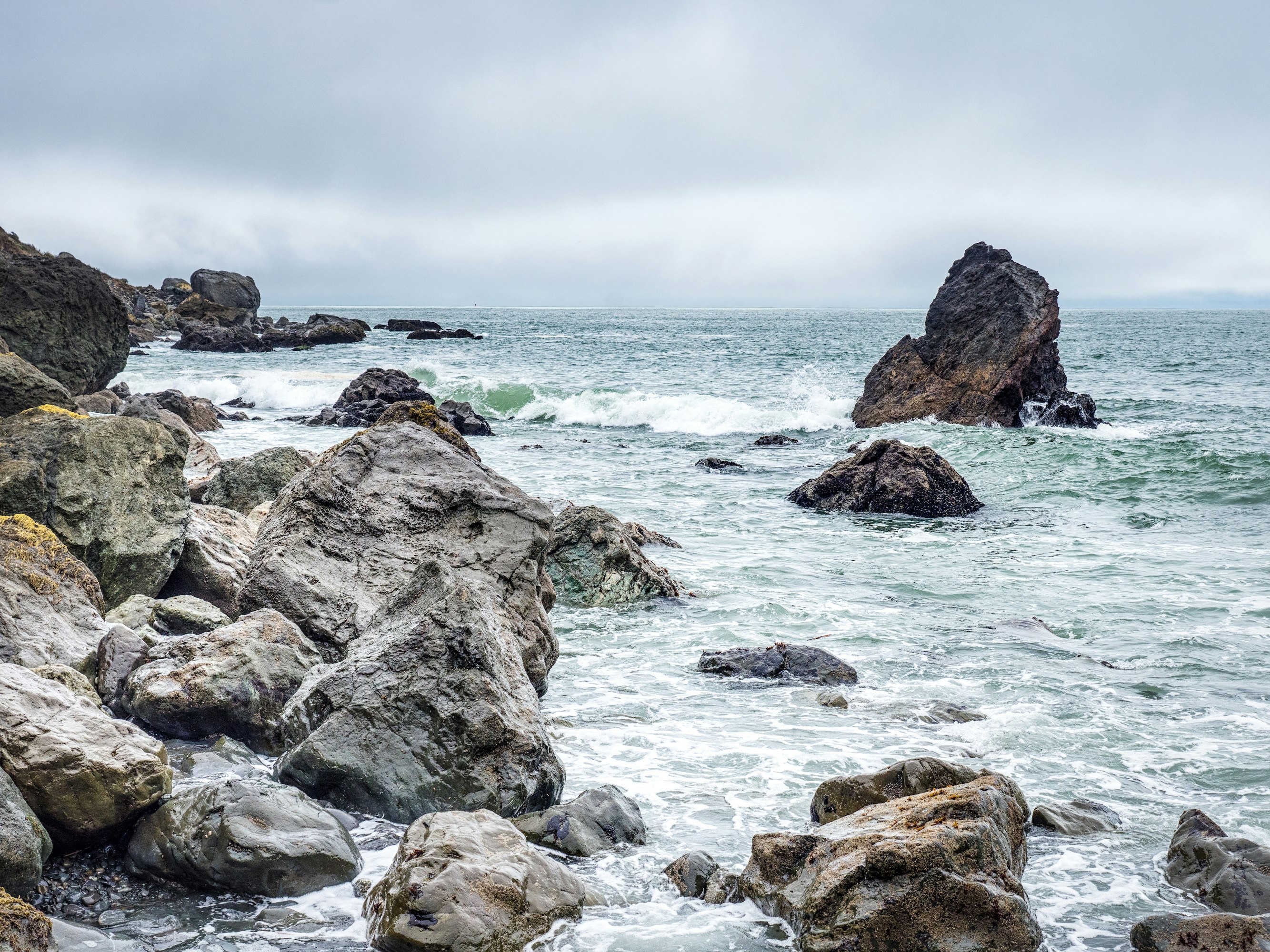 brown rock formation on sea under white clouds during daytime