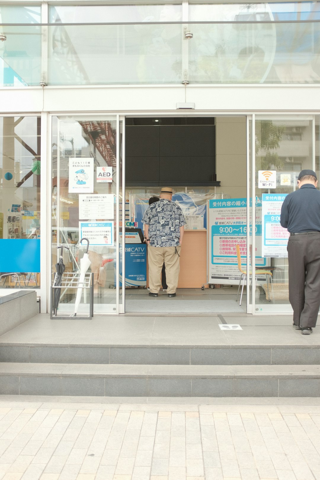 man in black shirt and blue and white floral pants standing beside glass door