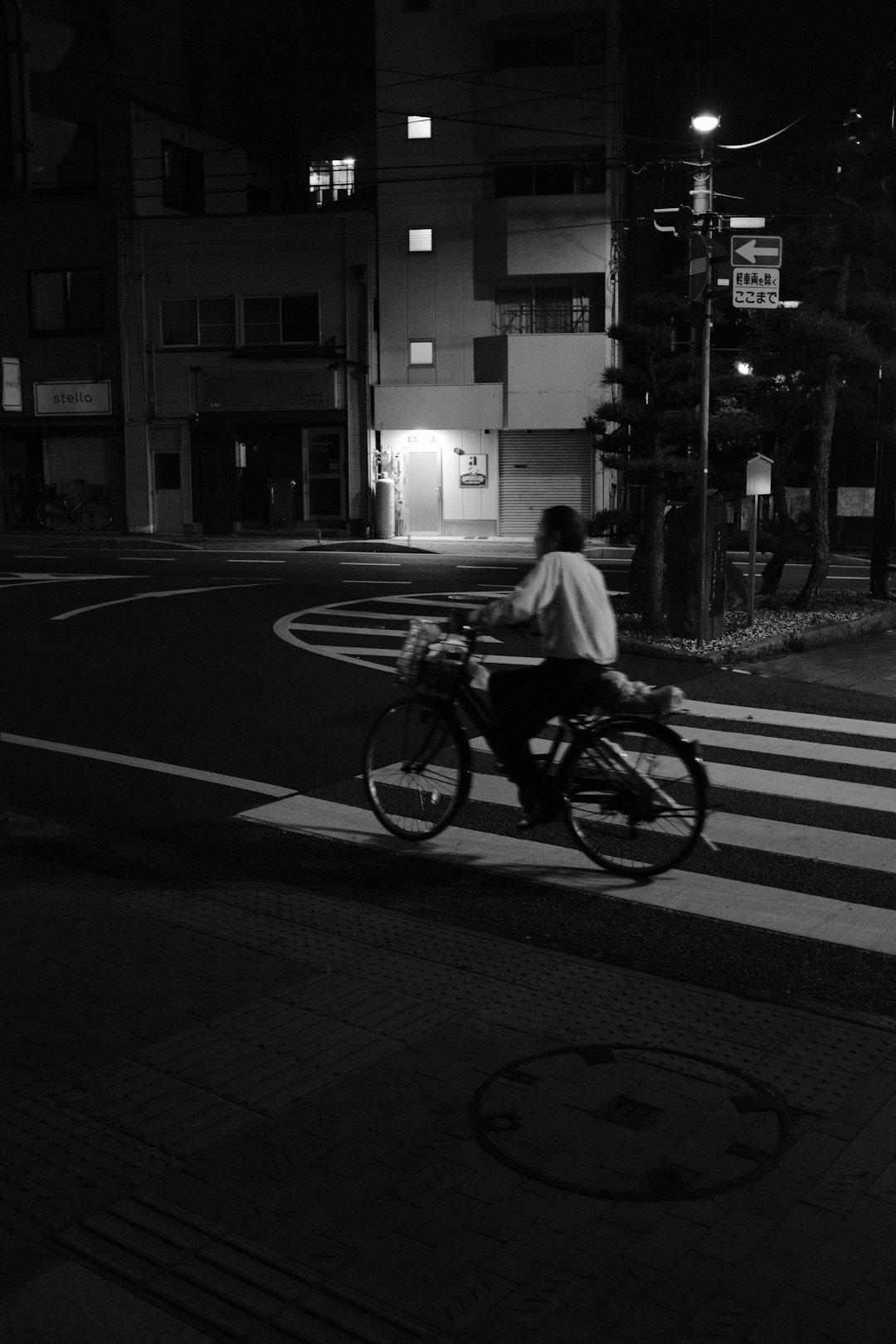 grayscale photo of man riding bicycle on pedestrian lane