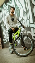 Artistic shot of a hoodie draped over a vintage bicycle parked near a graffiti wall.