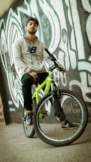 Artistic shot of a hoodie draped over a vintage bicycle parked near a graffiti wall.