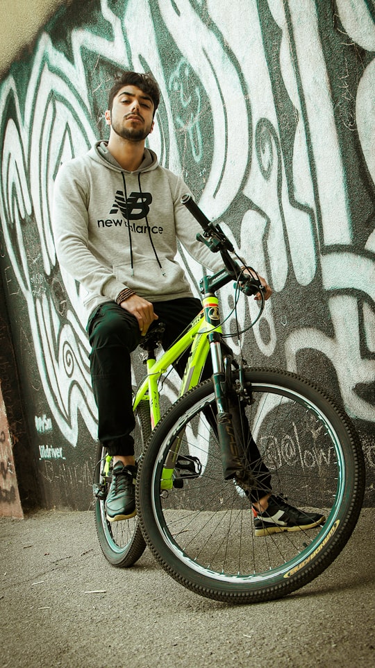 boy in gray hoodie and black pants riding on black and green mountain bike in İzmir Turkey