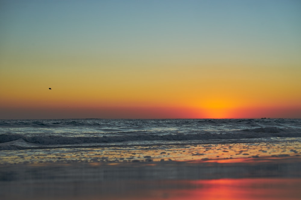 ocean waves crashing on shore during sunset