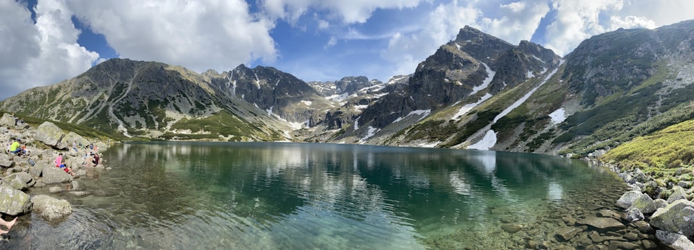 lago perto de montanhas cobertas de neve sob o céu azul durante o dia