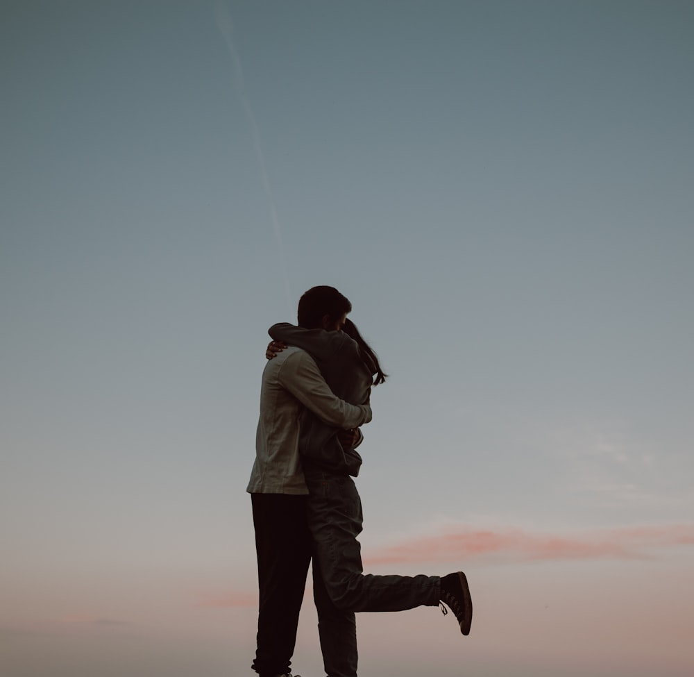 man in white hoodie and black pants carrying woman in white jacket