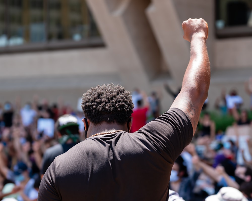 man in black shirt raising his right hand