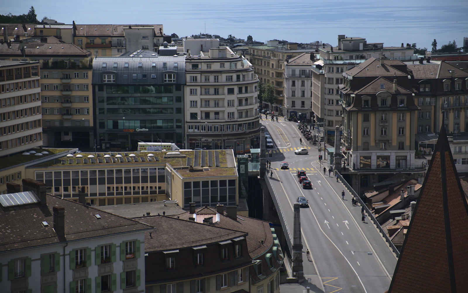 Cars moving along a broad street through a Swiss city