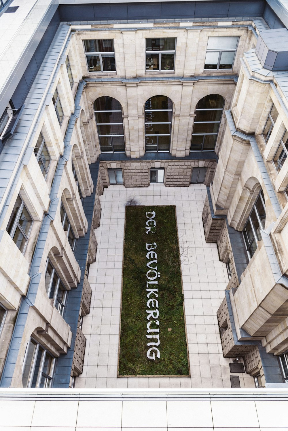 an aerial view of a building with a lawn in the center