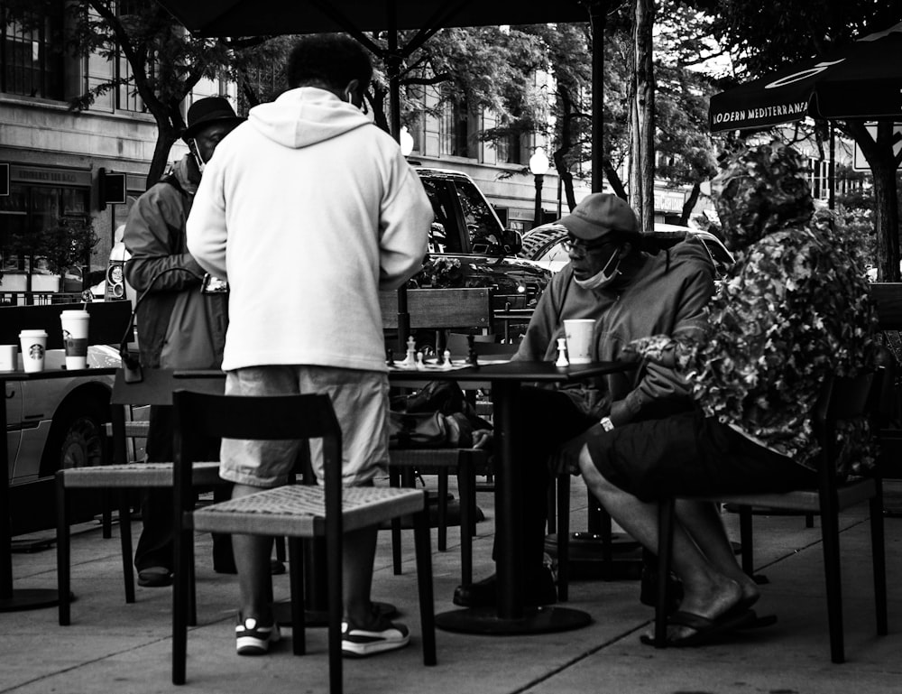 grayscale photo of people sitting on chair