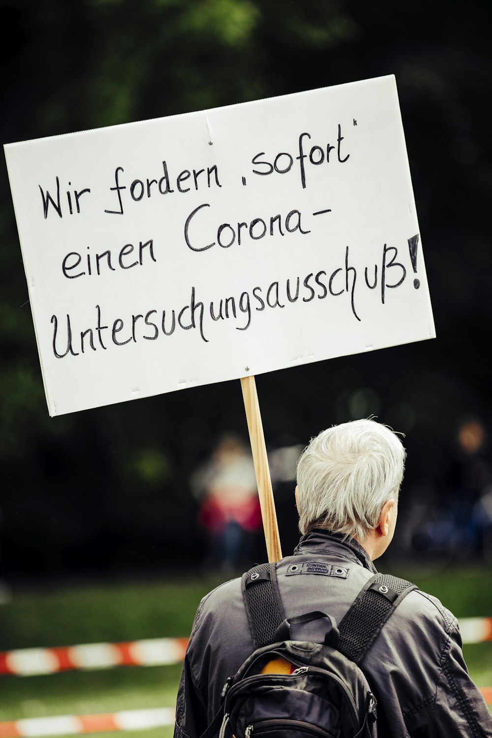 child in blue and gray jacket holding white and black signage