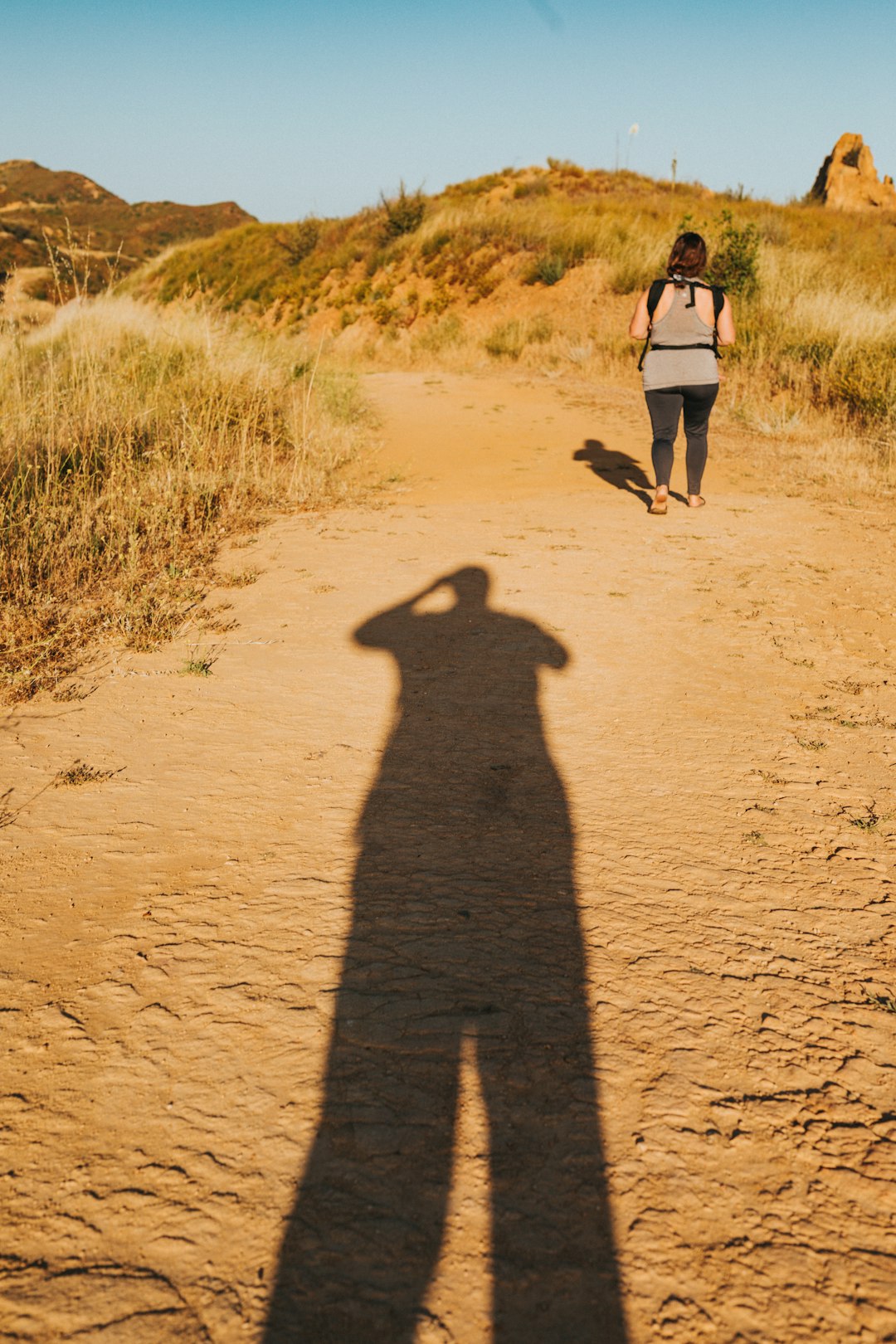 woman in black tank top walking on brown sand during daytime
