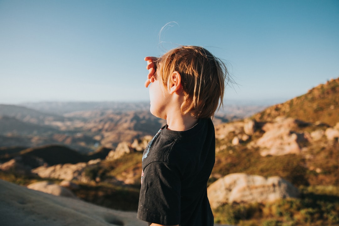 woman in black jacket standing on hill during daytime