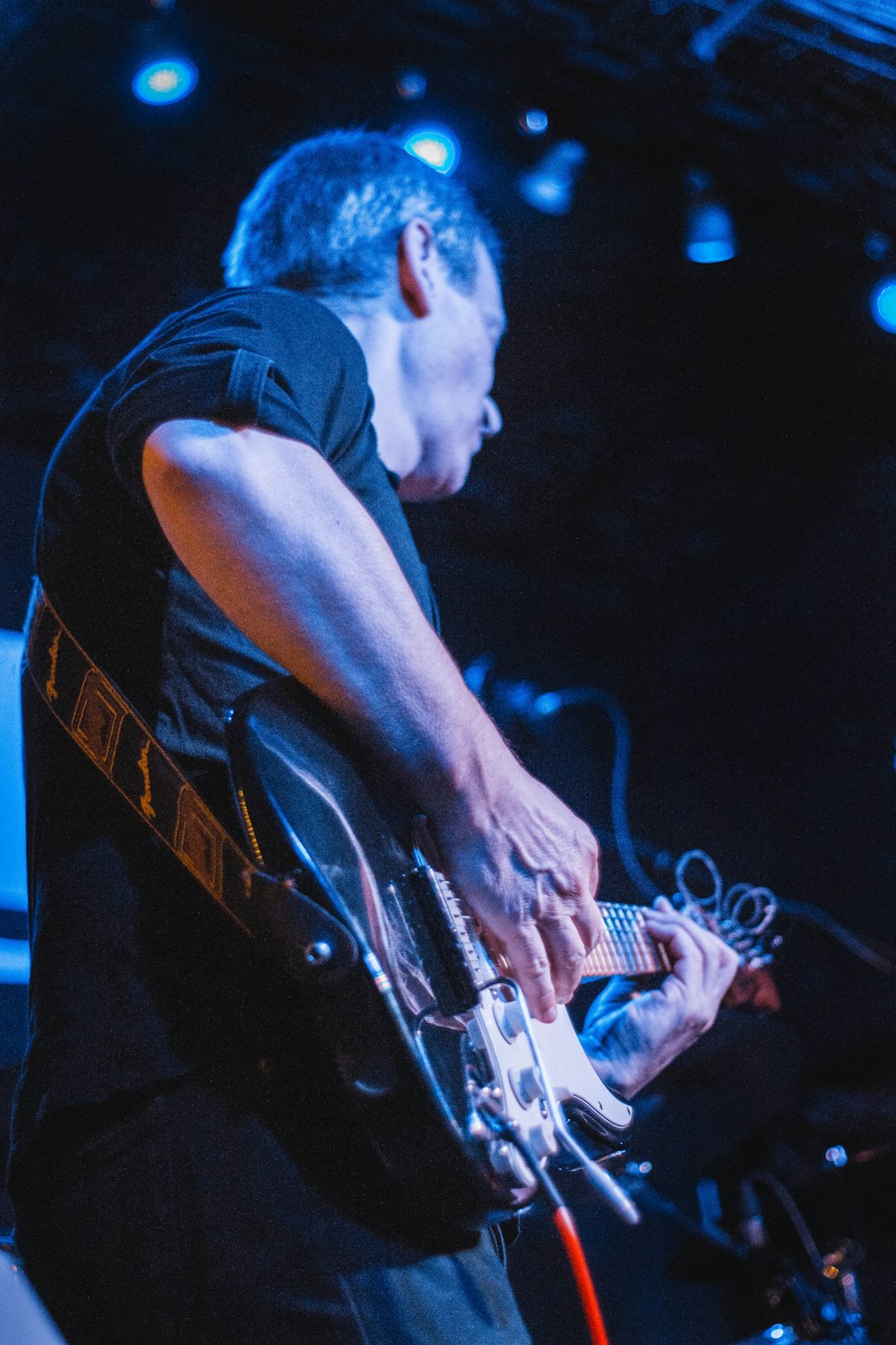 man in black tank top playing electric guitar