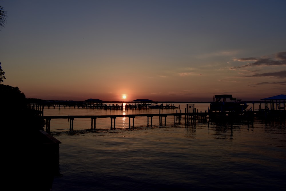 silhouette of dock on sea during sunset