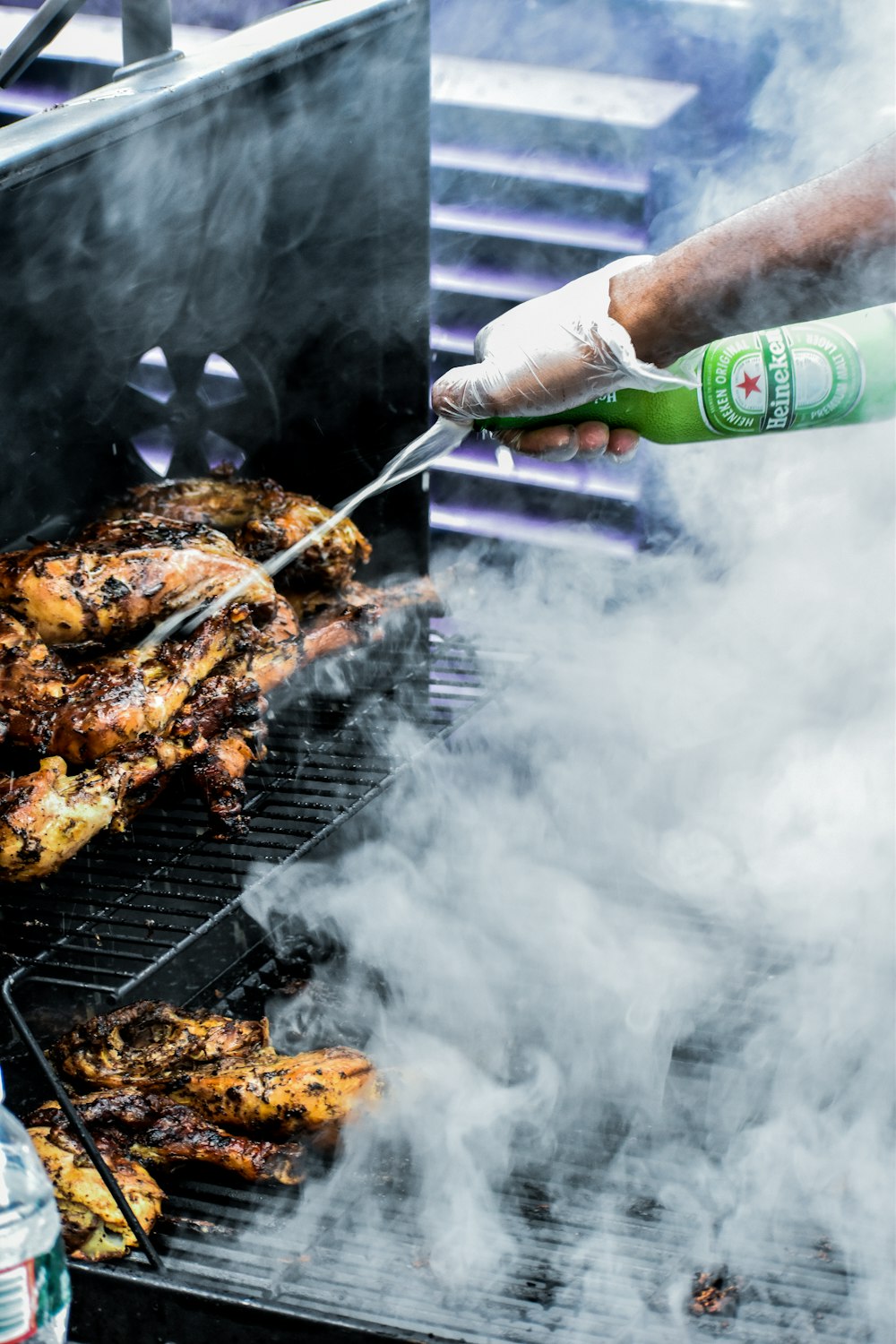 person holding green bottle and grilled meat