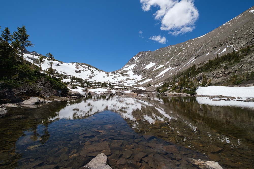 montagna innevata vicino al lago sotto il cielo blu durante il giorno