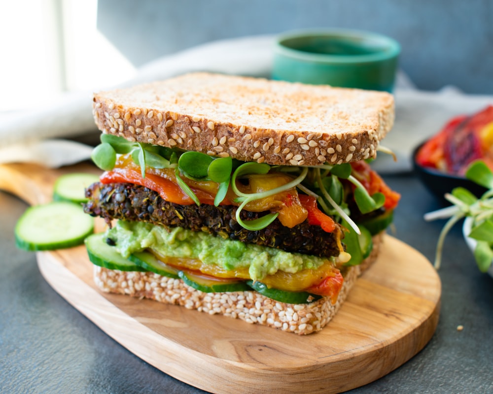 Burger mit Salat und Tomate auf braunem Holzschneidebrett