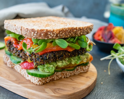 A stacked sandwich filled with fresh veggies and sauces on whole grain bread.