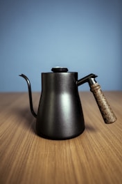 A stylish black cordless kettle glowing softly against a dark olive and golden backdrop.
