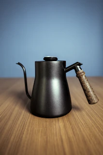 A compact, stylish electric kettle steaming gently on a wooden countertop.