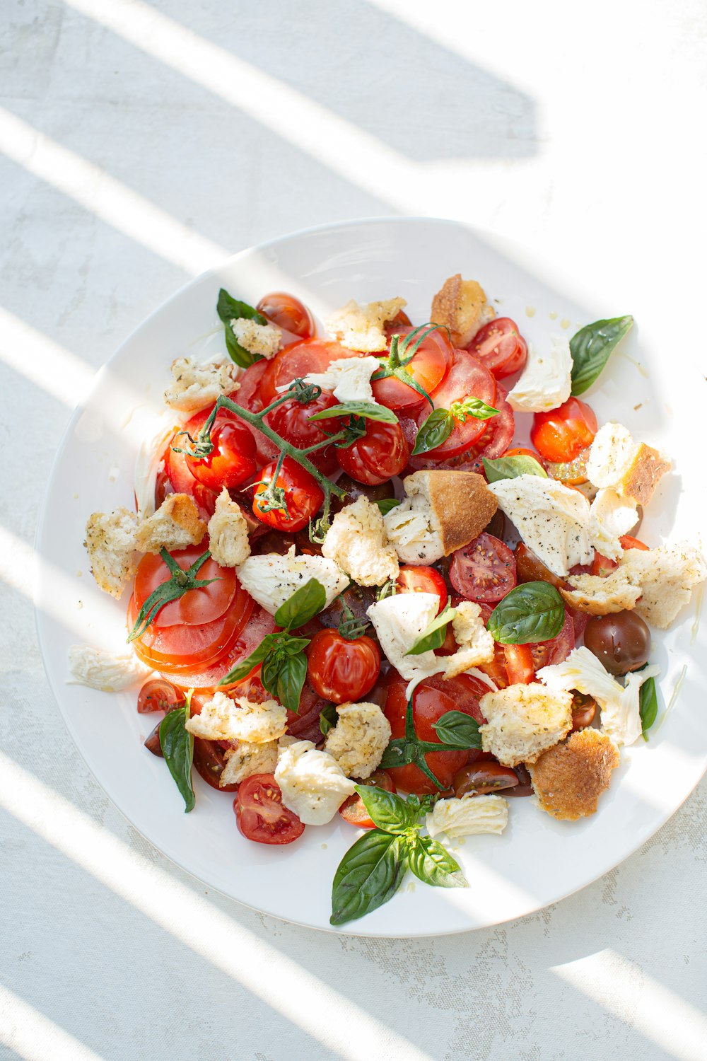 in Scheiben geschnittene Tomaten und grünes Blattgemüse auf weißer Keramikplatte