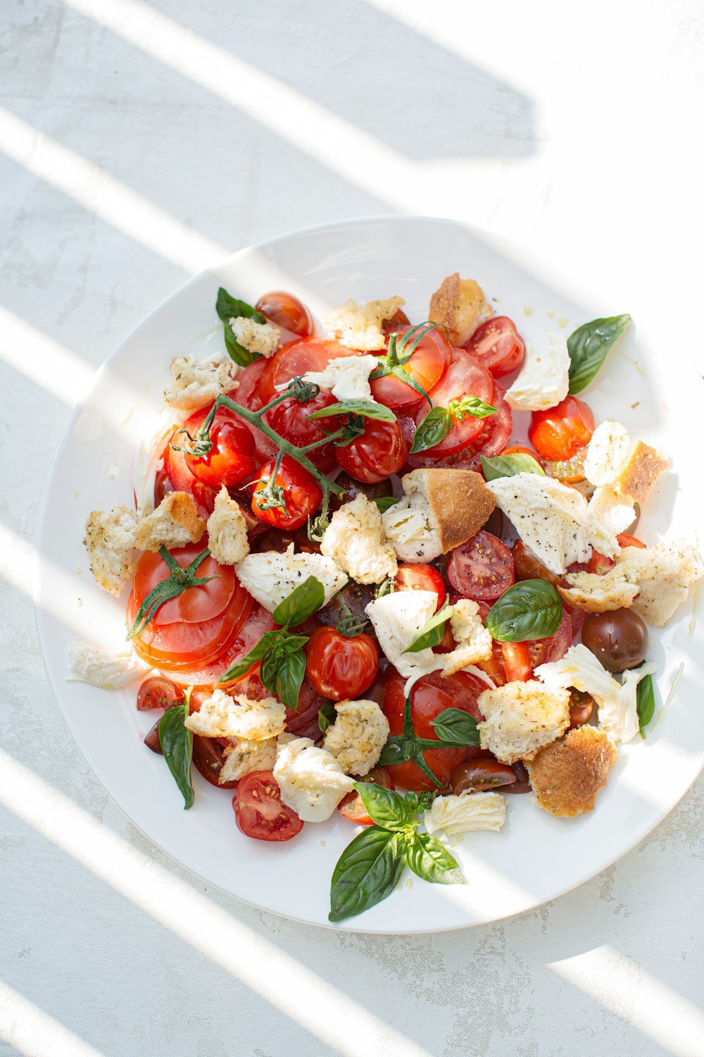 흰색 세라믹 접시에 얇게 썬 토마토와 녹색 잎 야채