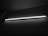 A long fluorescent light tube emits a bright white glow against a dark, textured wall, casting subtle shadows and creating a stark contrast.