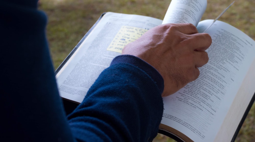 person in blue long sleeve shirt holding white book page