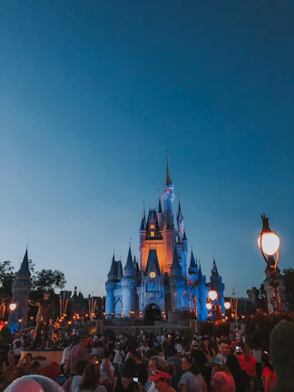 An atmospheric wide-angle view of a luxury gala with guests in elegant evening wear, bathed in warm gold and navy blue lighting.