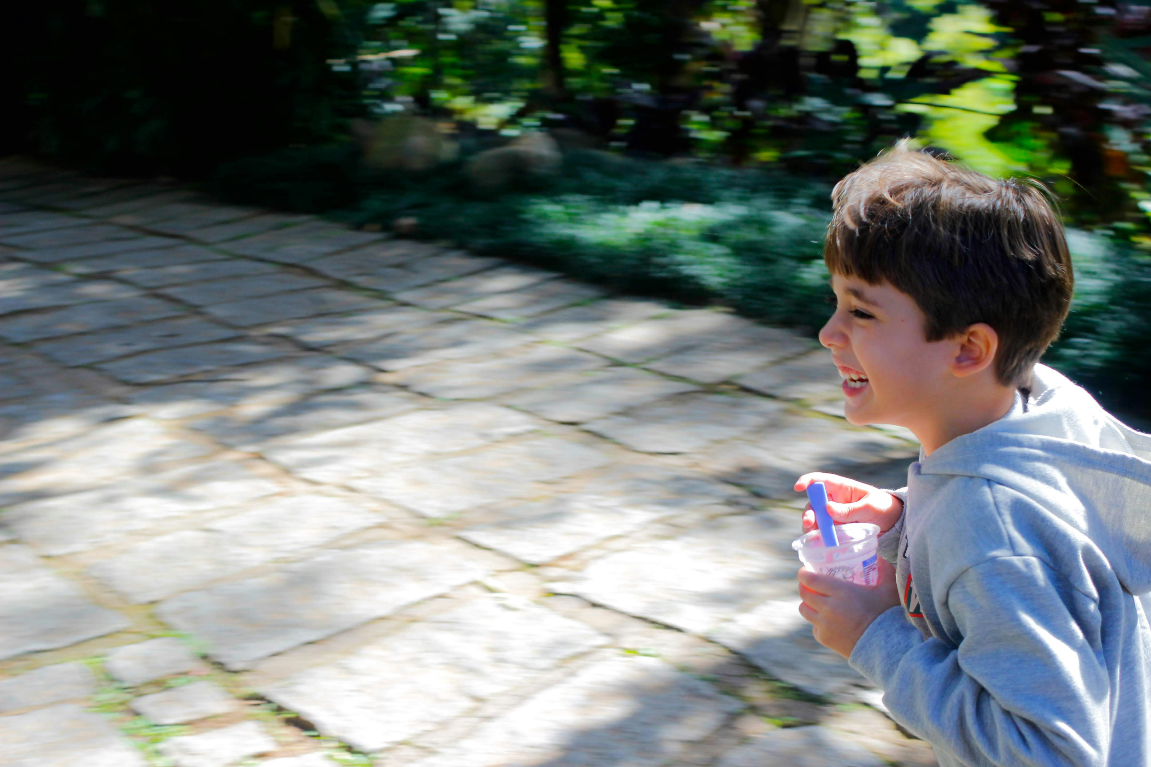 Garçon en chemise grise à manches longues tenant un jouet en plastique violet et blanc