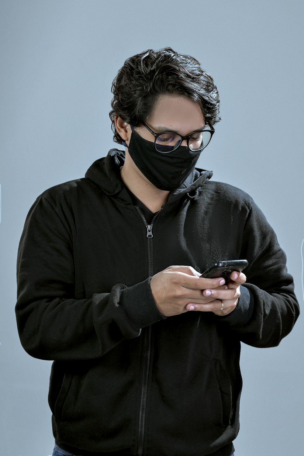 Hombre con chaqueta negra con cremallera y gafas de montura negra