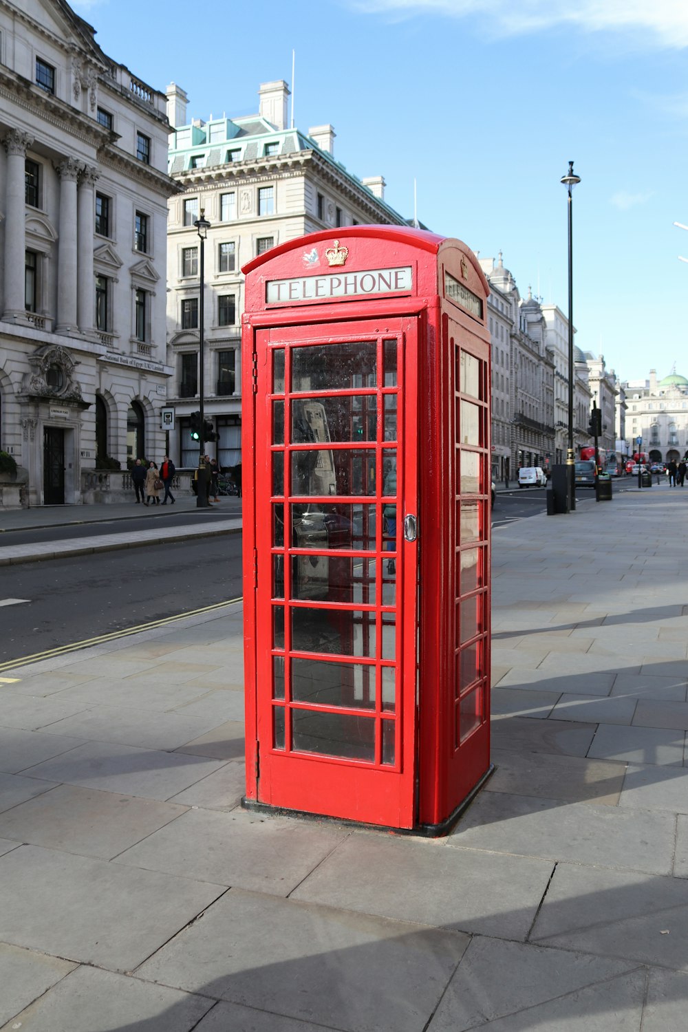 red telephone booth on sidewalk during daytime