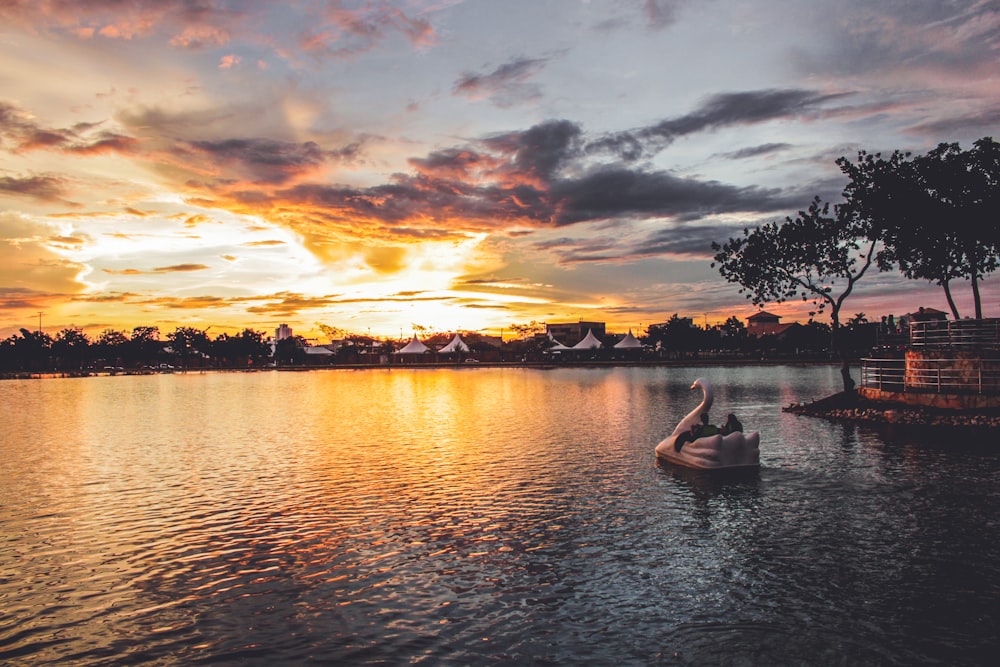 silhouette of 2 people riding on boat on water during sunset