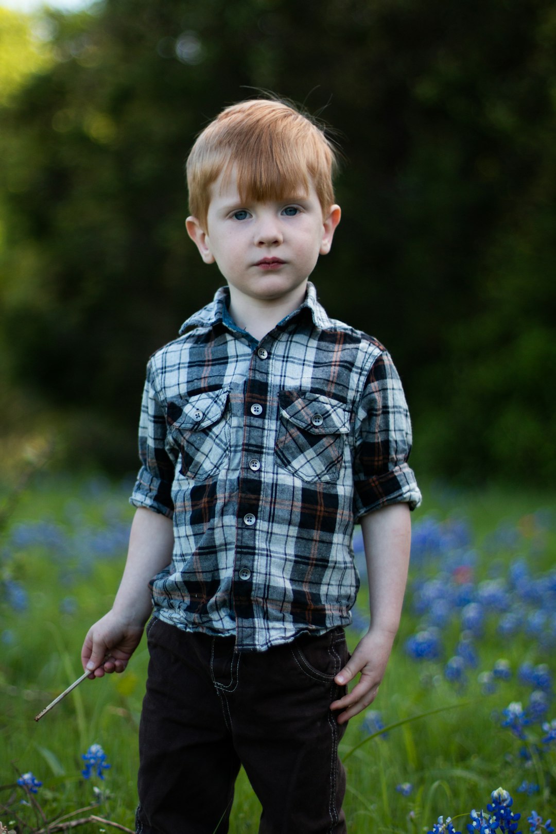 boy in blue and white plaid button up shirt standing on green grass field during daytime