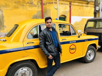 man in black leather jacket standing beside yellow car