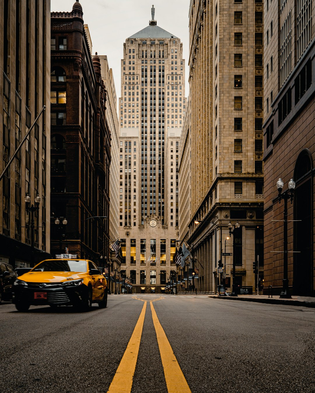 yellow car on road in between high rise buildings during daytime