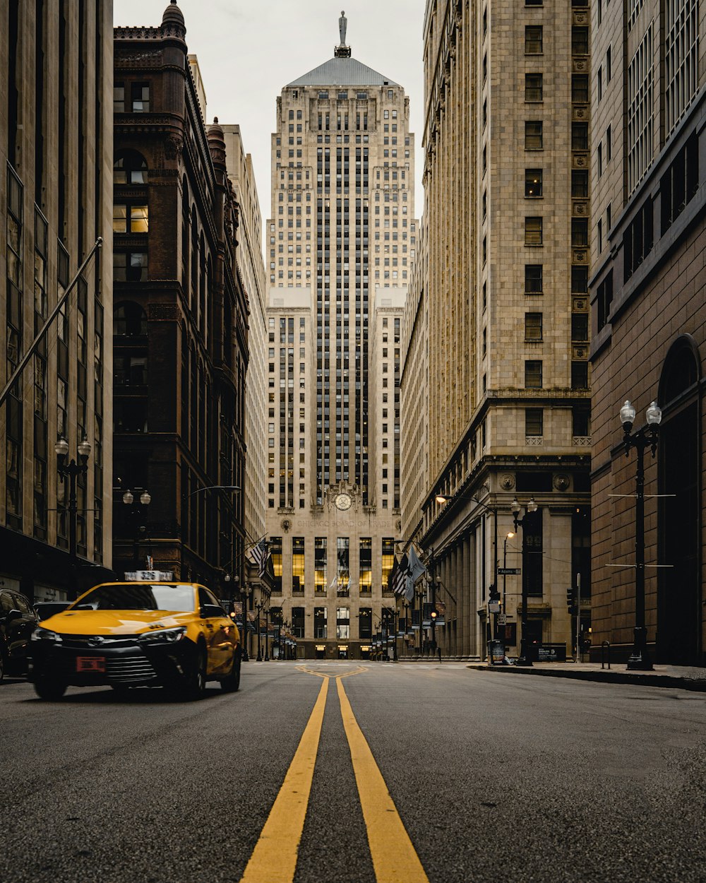 yellow car on road in between high rise buildings during daytime