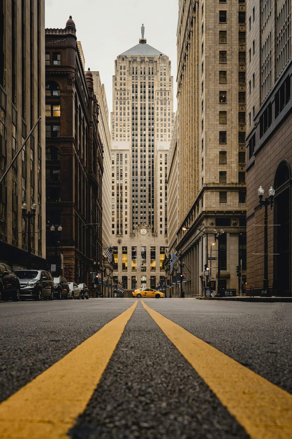 yellow and black pedestrian lane in between brown concrete buildings during daytime