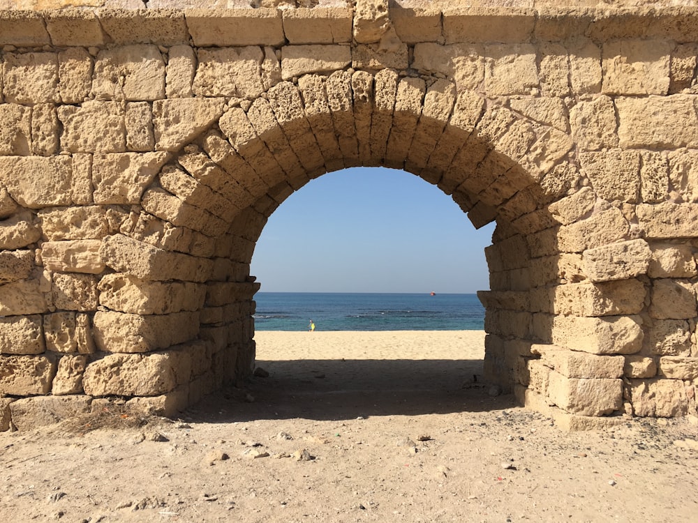 Arco de hormigón marrón cerca del mar durante el día