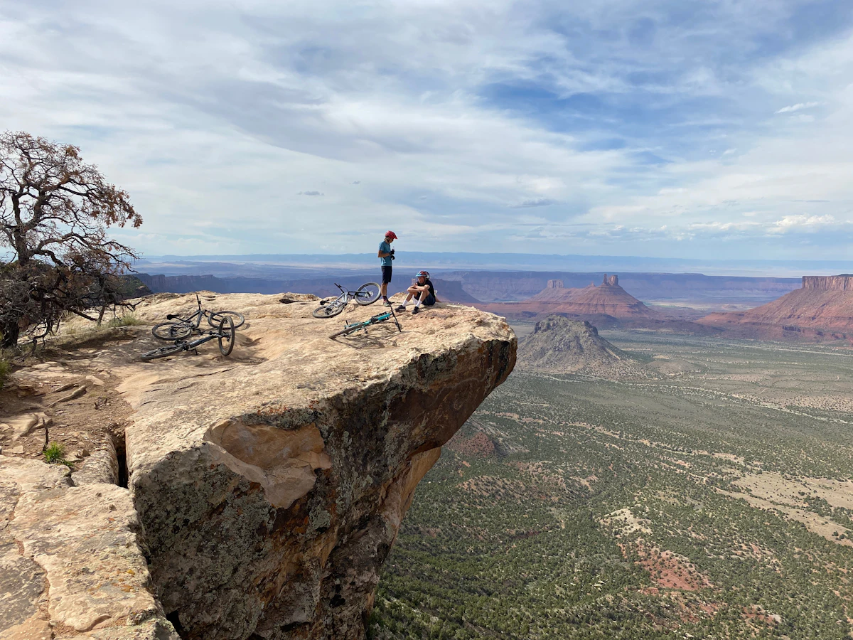 Mountain bikers resting on a sandstone ledge above a desert valley near Moab