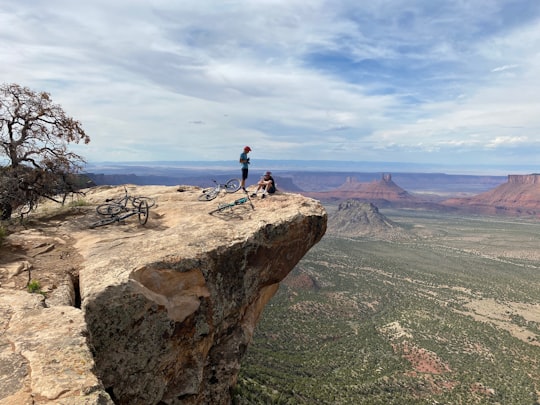 man in black jacket standing on brown rock formation during daytime in Moab United States