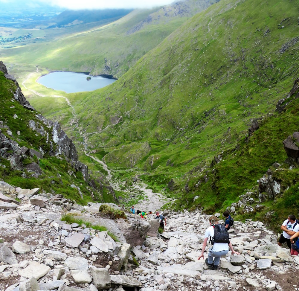 people walking on rocky road near green mountains during daytime